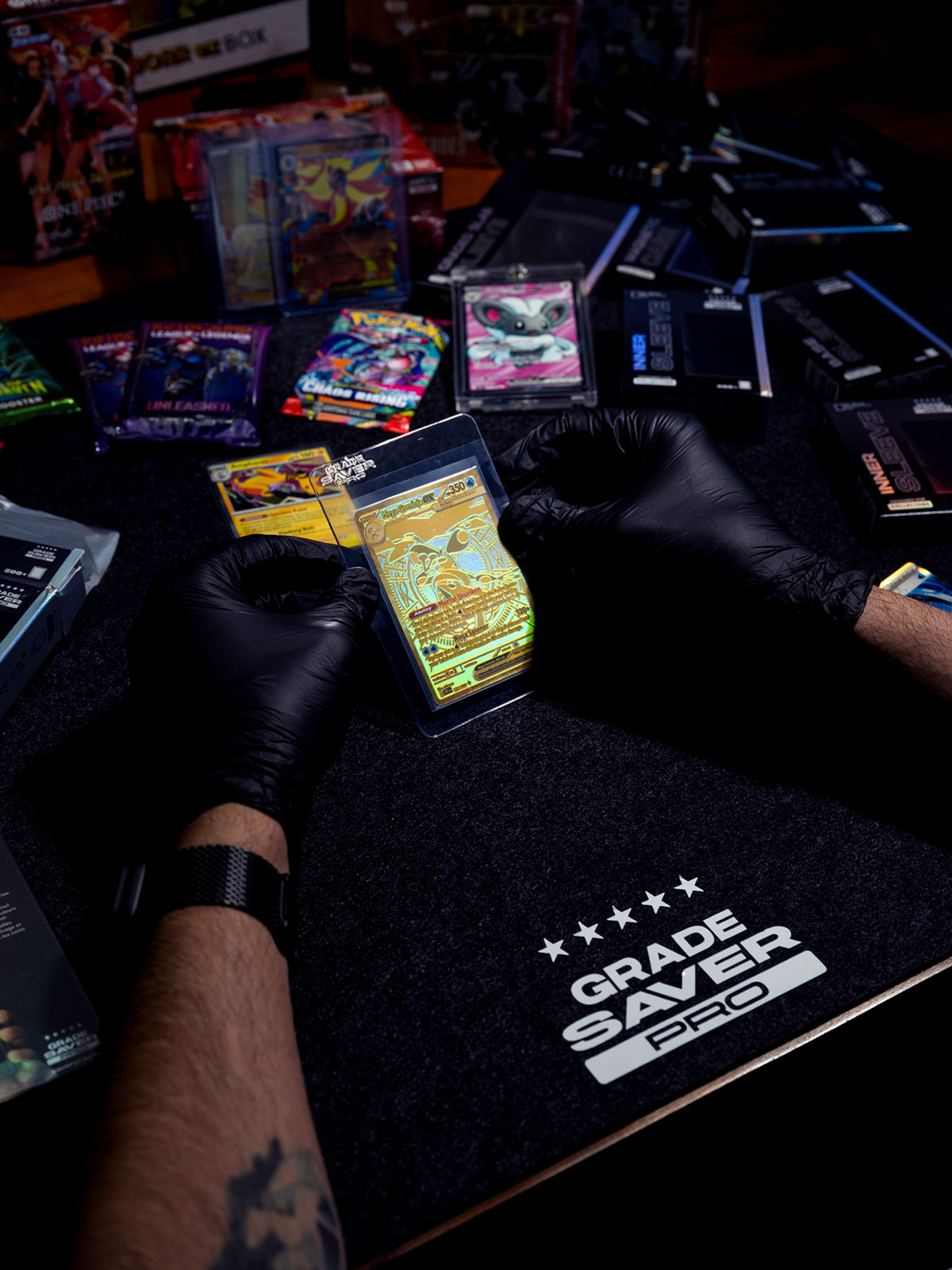 Two hands are holding a Pokémon card in a semi-rigid shield, ready for grading. In the background, you can see a bunch of booster packs and “Grade Saver Pro” products.
