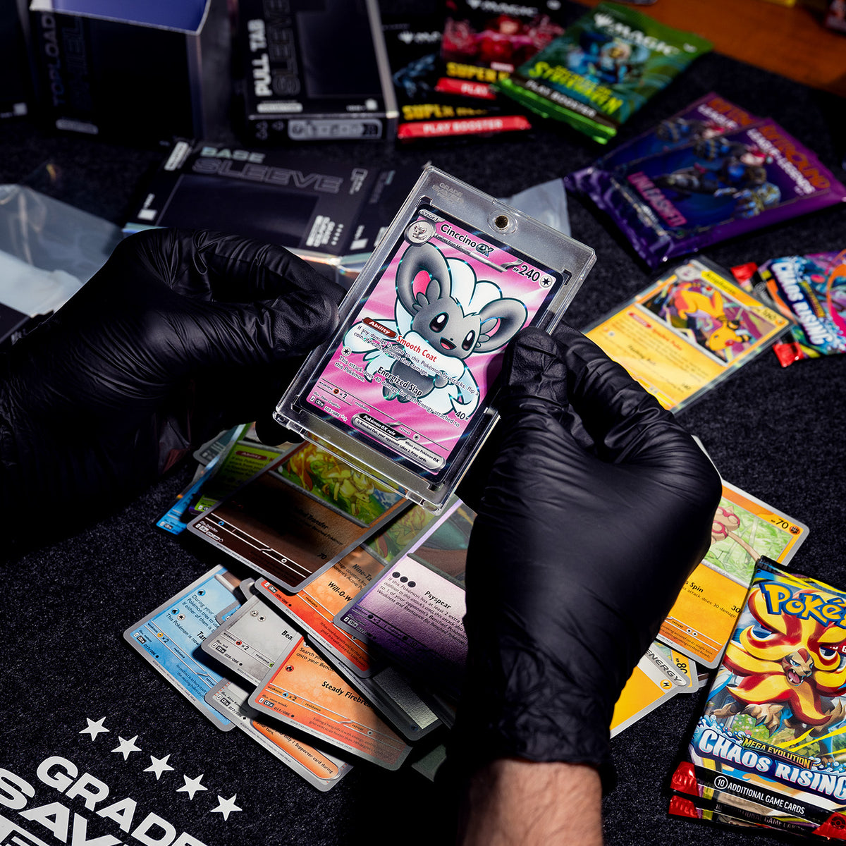 Two hands holding a Pokémon card in a magnetic sleeve. Several booster packs can be seen in the background.